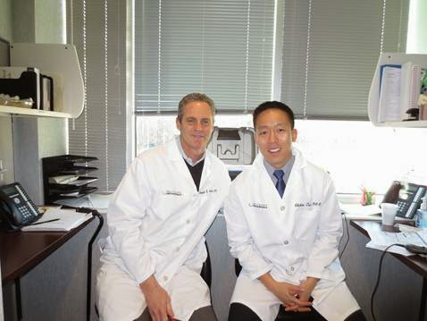 Ken Montgomery, MD and Chihao Tsui, PA-C seated together in white coats in their clinic office