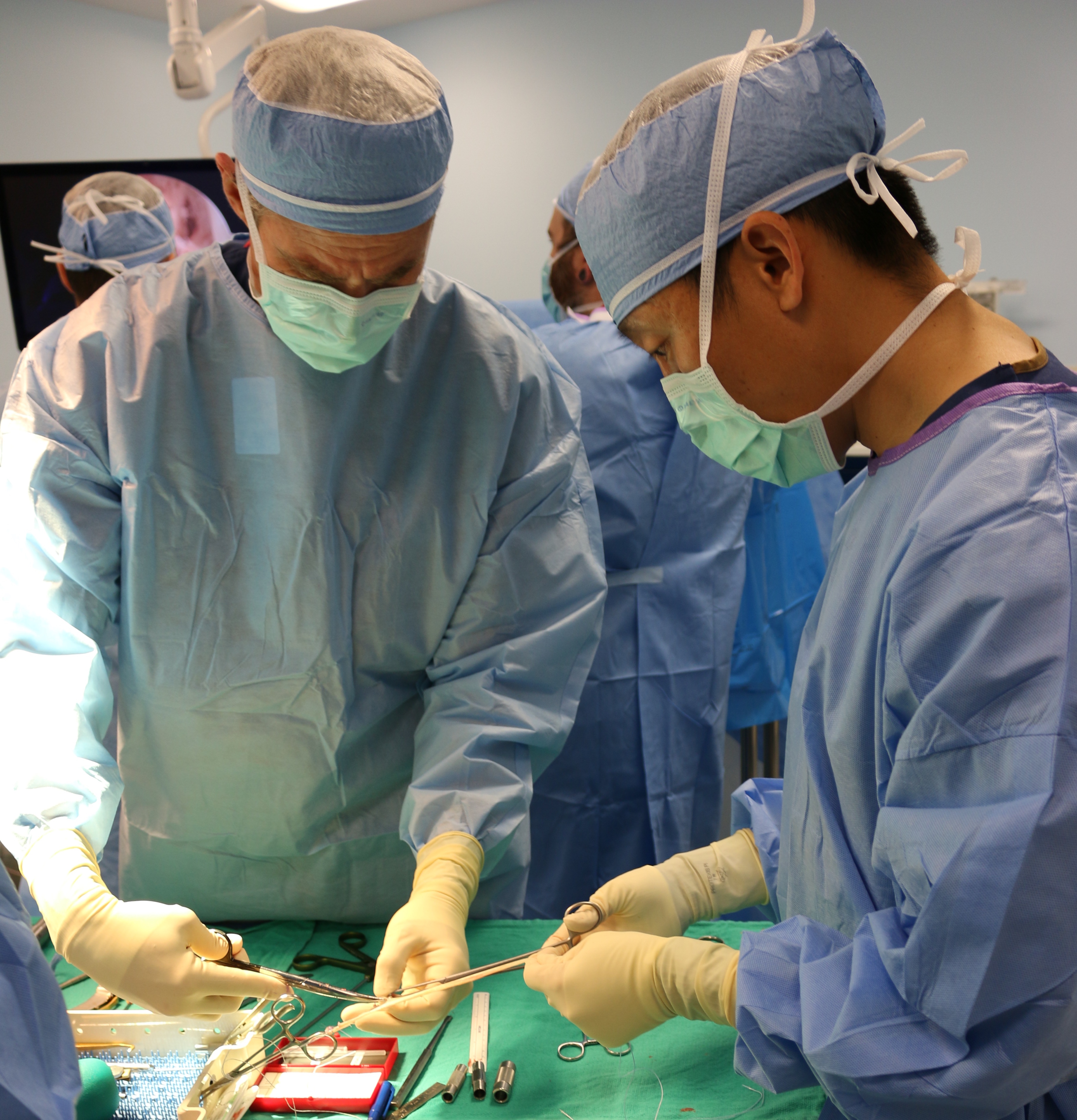 Ken Montgomery, MD and Chihao Tsui, PA-C in surgical gowns working together in the operating room